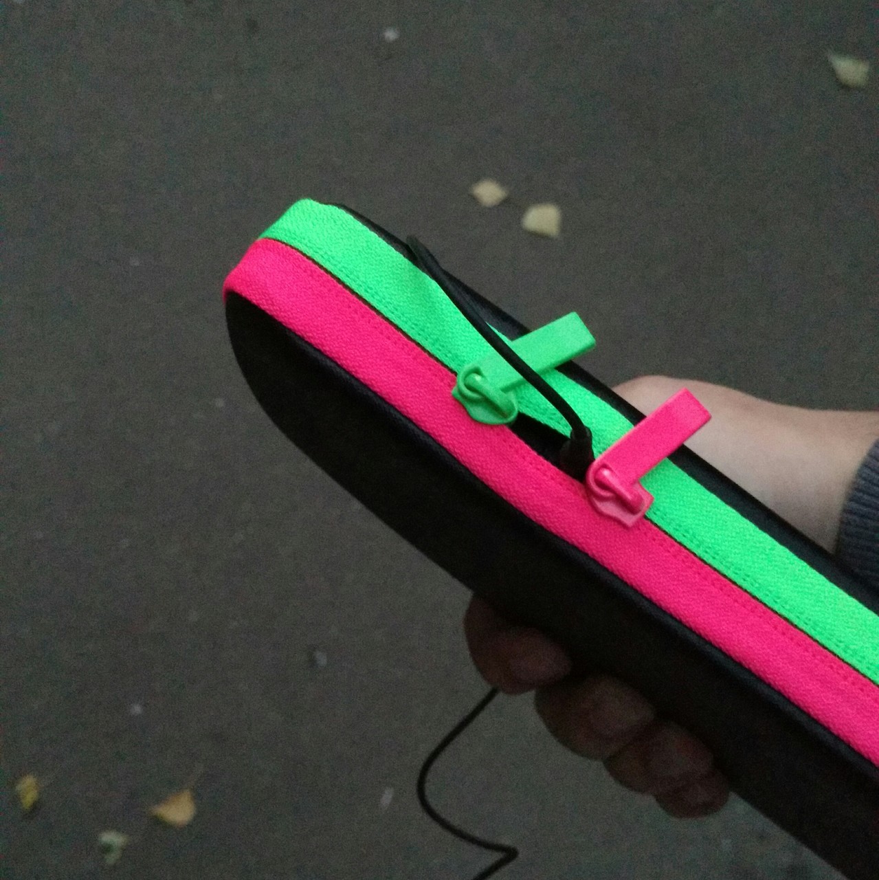 photo of a splatoon 2-styled carrying case for the nintendo switch, with the
zipper being almost completely shut with the exception of a small gap, through
which a headphone jack is connected.